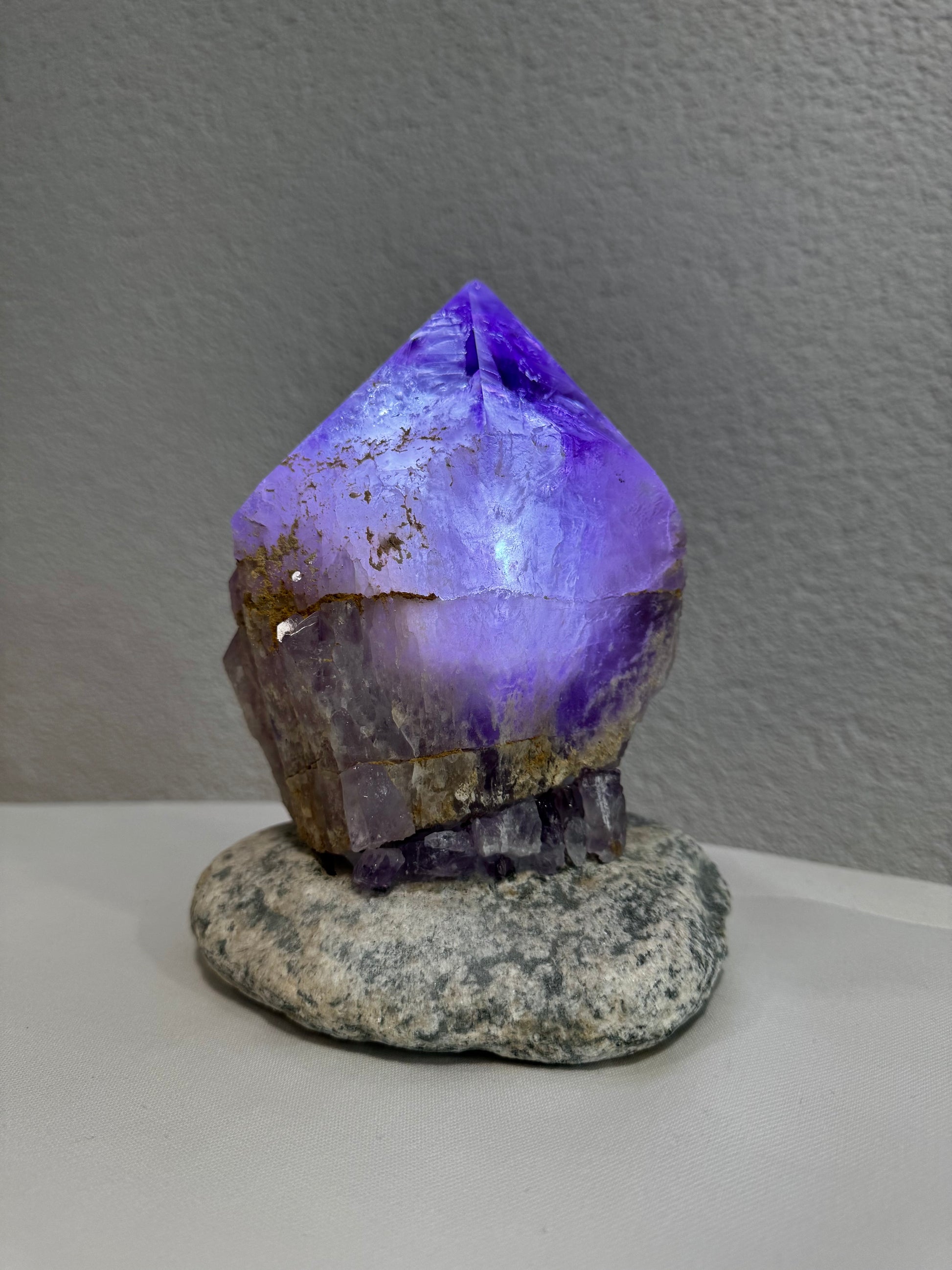 Leuchtende Amethystspitze auf natürlichem Stein, einzigartige handgefertigte Lampe aus Uruguay, perfekt als dekoratives Element, im Mineralienhotel Natznerhof erhältlich