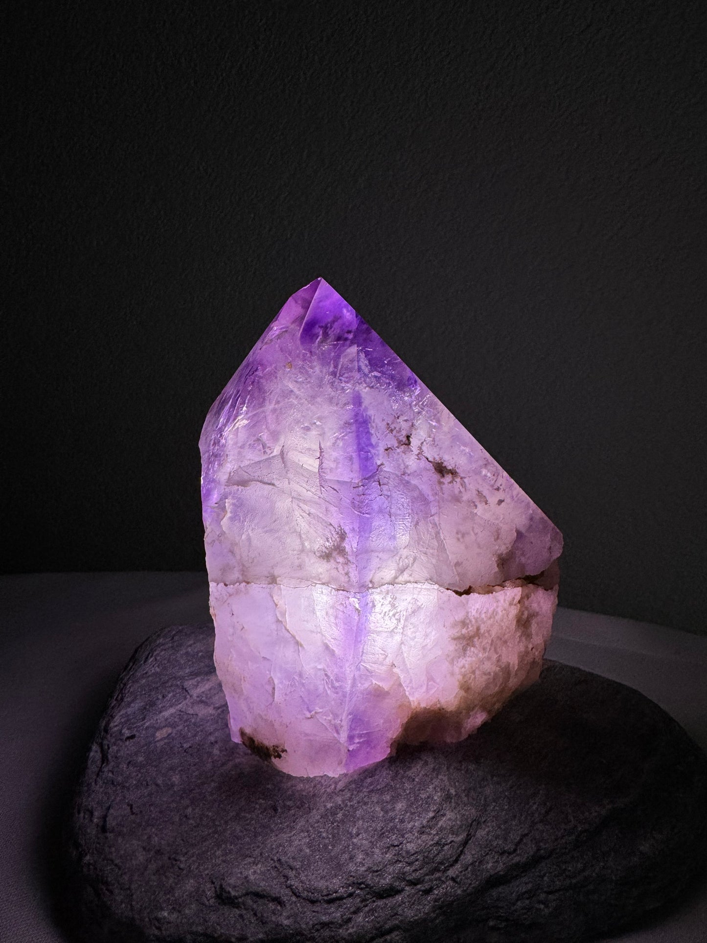 Leuchtender Amethystkristall von oben fotografiert, strahlende Farben in lila und violett auf dunklem Hintergrund