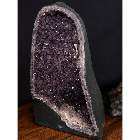 Amethyst-Druse mit dunklen violetten Kristallen und Kalzitkristallen auf Steinsockel