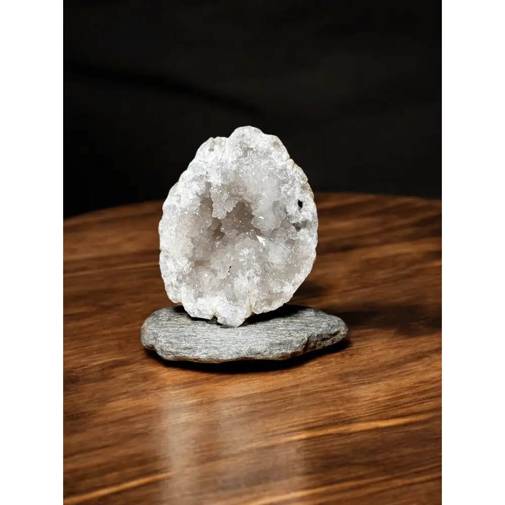 Leuchtende Quarzdruse mit funkelnd weißem Geode auf grauem Stein
